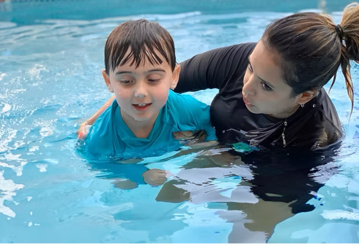 Swim instructor teaching child water safety skills