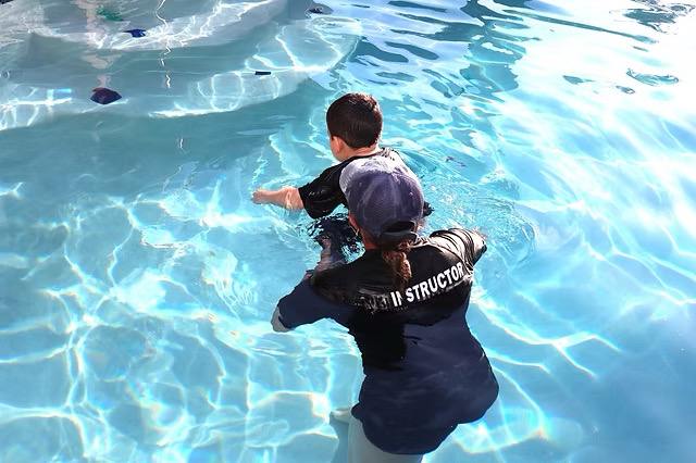 Instructor guiding child through swimming techniques